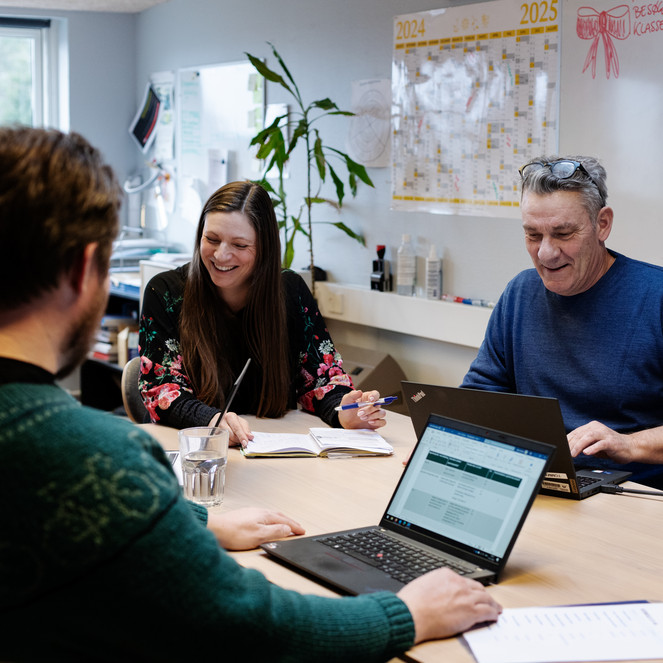 Tre personer om et bord holder møde